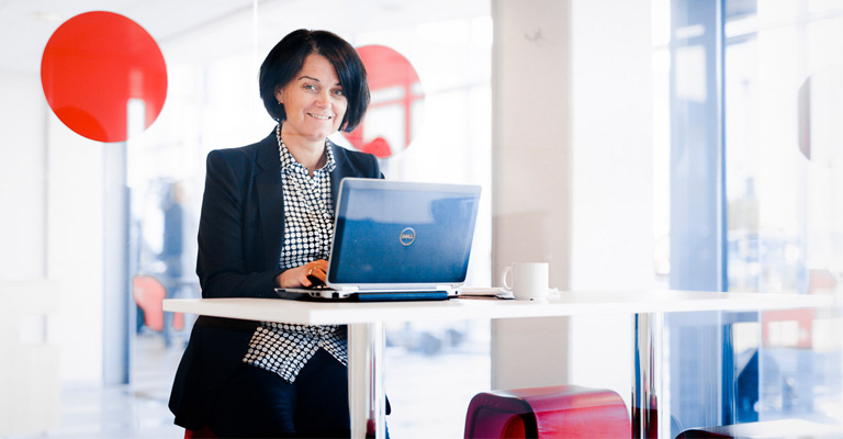 Kvinne sitter ved kontorpult med PC